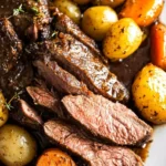 Slow-cooked crock pot venison roast sliced and served with tender carrots and baby potatoes