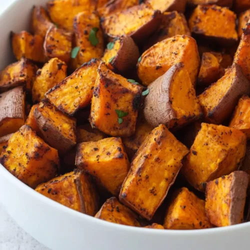 Ranch Roasted Sweet Potatoes 4 Close-up of crispy ranch roasted sweet potatoes in a white bowl, showing golden brown edges and herb seasoning.