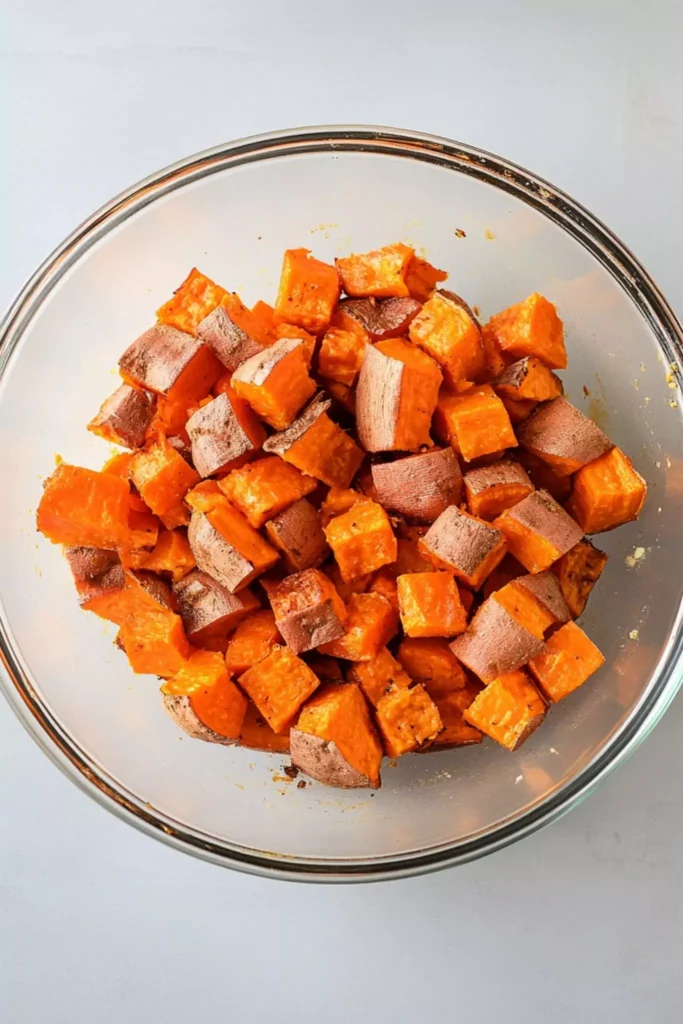 Ranch Roasted Sweet Potatoes 1 Uncooked sweet potato cubes in a glass bowl, tossed with oil and ranch seasoning, ready for air fryer roasted potatoes.