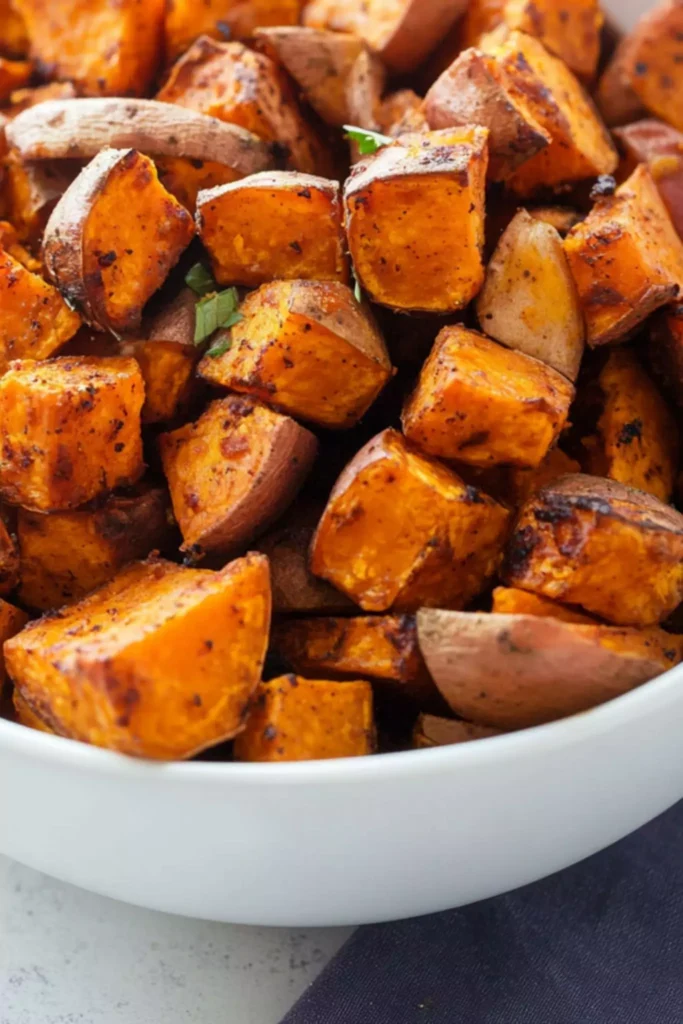 Ranch Roasted Sweet Potatoes 2 Close-up of golden brown ranch roasted sweet potatoes in a white bowl, showing crispy edges and seasoned skin.