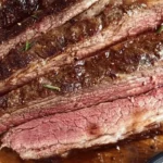 Sliced keto beef chuck roast on a wooden cutting board, cooked medium with a juicy, tender texture