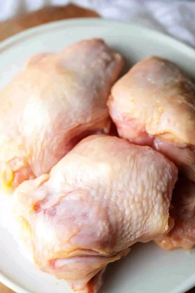 Raw frozen chicken thighs on white plate